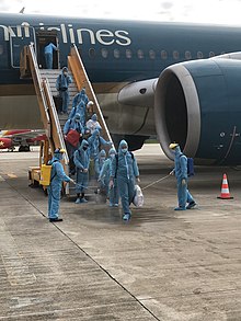 Passengers with full medical hazmat suits disembarking from a repatriation flight operated by Vietnam Airlines. On the ground, there were staffs and crews spraying sanitizing solution onto the deboarded passengers. Repatriation VNA.jpg