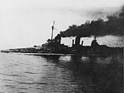 A large gray warship, heavily flooded, its deck is nearly submerged. Thick black smoke pours from the funnels. An in-photo caption reads: "Seydlitz nach Skaggerak-schlacht", or "Seydlitz after the Skaggerack battle."