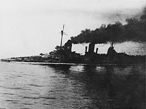 A large gray warship, heavily flooded, its deck is nearly submerged. Thick black smoke pours from the funnels. An in-photo caption reads: "Seydlitz nach Skaggerak-schlacht", or "Seydlitz after the Skaggerack battle."