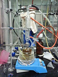 A reflux set-up with conically tapered ground glass joints connecting the coil condenser with an adapter to allow inert gas (nitrogen or argon) to leave the vessel (top) and two-necked flask. Another ground glass joint connects the second neck to another adapter for introduction of an inert gas. Toluene with sodium-benzophenone.jpg