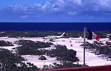 Avion sur la piste d'aviation de l'île Tromelin avec un drapeau français flottant en 1981.