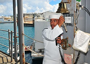 US Navy 100804-N-5006D-005 Seaman Apprentice Adam McMahon prepares to ring the ship's bell and announce the departure of Rear Adm. Doug McAneny.jpg