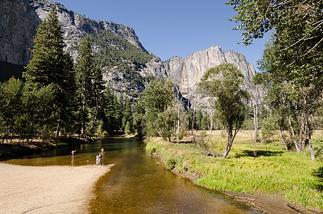 Merced River in Yosemite Valley with people walking through the water photographed from Swinging Bridge