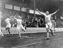 Photographie représentant l'arrivée du 100 mètres avec Charley Paddock les bras levés.