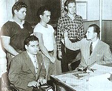 Three of the boys standing before the district Attorney, who holds up the bullwhip used in one of the attacks. 3 Brooklyn Thrill Killers with Stenographers and DA.jpg