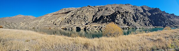 Cairnmuir Mountains from Lake Dunstan, Central Otago. The earthworks and terraces of the Cairnmuir Landslip is visible in the upper centre-left of the photo, while the Cairnmuir tunnel used to drain groundwater from the basal shear zone is visible in the centre of the photo, several metres above lake level. CairnmuirMountains.jpg