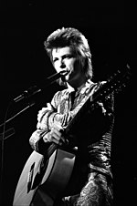 David Bowie contributed vocals to "Cool Cat" and "Under Pressure", though his parts on the former were removed at his request. David Bowie, as Ziggy Stardust, performing at the Santa Monica Civic Auditorium.jpg