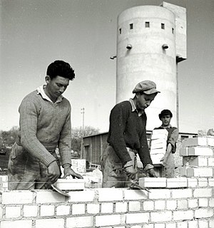 הקמת בתים חדשים בקיבוץ אלונים בעמק יזרעאל, 1 בפברואר 1946, צילומו של זולטן קלוגר. בצילום, חלוצים עובדים בבנייה ביישוב. מאחור: הממגורה של היישוב.