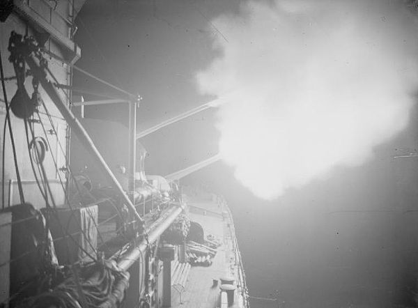 Flashes from the 6-inch guns of Orion can be seen against the darkness during a nighttime bombardment of enemy positions on the Garigliano River.