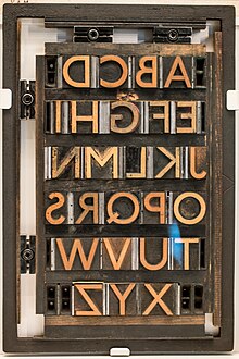 Johnston wood type, the corporate typeface of the London Underground system, with a humanist sans-serif design different to nineteenth-century grotesque wood types. The wood type is locked in a chase used for printing with spacing materials Johnston Letters (34228414755).jpg