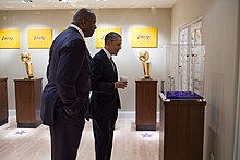 Magic Johnson's trophy room, featuring several Larry O'Brien Championship trophies in the background Obama at Magic Johnson's trophy room.jpg