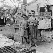 An impoverished American family living in a shanty, 1936 Poor mother and children, Oklahoma, 1936 by Dorothea Lange.jpg