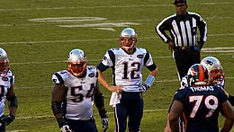 Tom Brady con la mano sul fianco durante una partita di football americano.