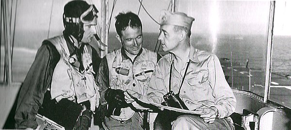 Captain John S. Thach (right) as commanding officer of the escort aircraft carrier USS Sicily (CVE-118) during the Korean War, discussing a mission wi