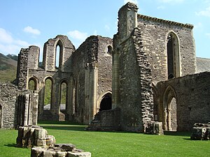 Nave de iglesia en ruinas que da a un coro del que se conserva el ábside, así como un brazo del crucero.