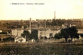 Vista di una città operaia su una vecchia cartolina: piccoli condomini e camini di fabbrica.