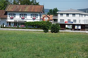 Weißes zweistöckiges Gebäude mit gewölbtem Dach und Holzunterstand