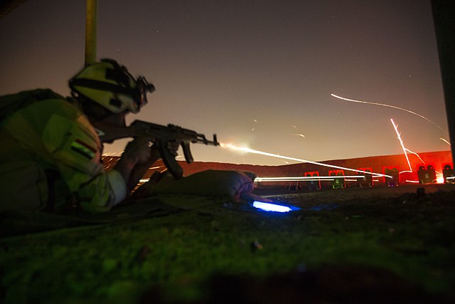 An Iraqi soldier assigned to the Security Battalion, Nineveh Operations Command, fires his AK-47 rifle during night range training at Camp Taji, Iraq,