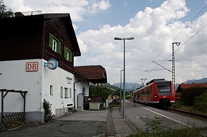 Red train next to two-story building with gabled roof