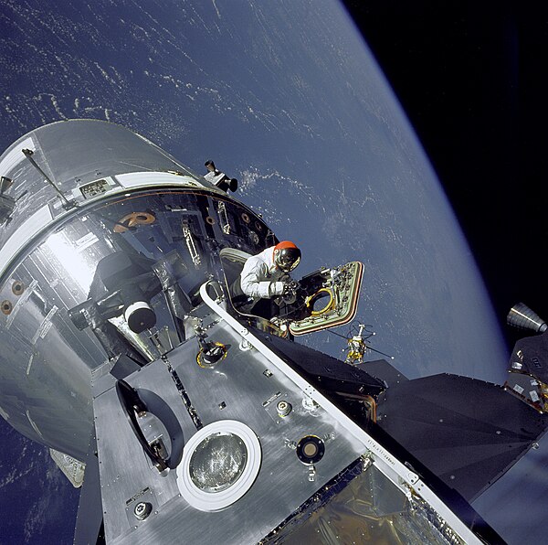 CM pilot David Scott performs a stand-up EVA from CM Gumdrop, seen from docked LM Spider