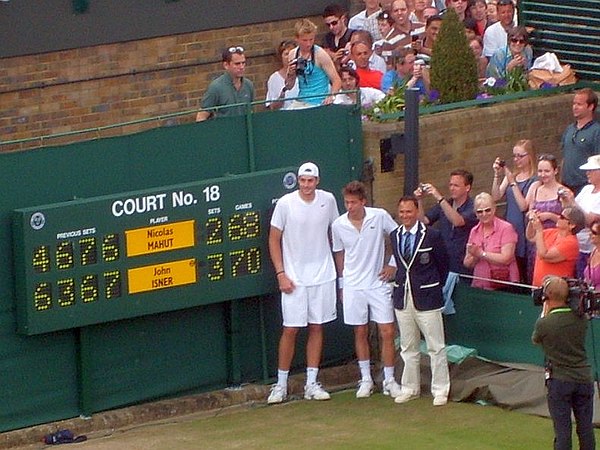 Players and umpire pose by the scoreboard after the match