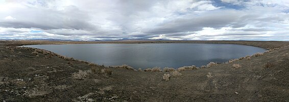 panorama jezera Big Soda za zamračeného dne, ukazující vodu v jezeře, strmé strany kráteru a okolní pouštní krajinu