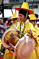 Músicos coreanos con vestidos típicos, tocando el tambor janggu.