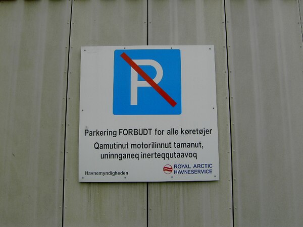 A bilingual sign in Nuuk showing the contrast between Danish and Kalaallisut. The sign translates to "parking forbidden for all vehicles."