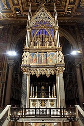 The high altar and the 14th-century Gothic ciborium. The relic of the original wooden altar used by Saint Peter comprises the high altar. Above the ciborium are the appearances of Sts. Peter and Paul.[8]