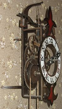 Modern reproduction of an early verge and foliot clock. The pointed-tooth verge wheel is visible, with the wooden foliot rod and suspended weight above it. Waagbalkenuhr Metall Nachbau 02.jpg