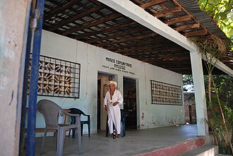 Amuzgo man in traditional dress in front of the Amuzgo Community Museum XochistlahuacaCommMuseum01.JPG