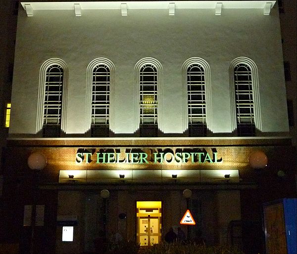 The art deco entrance of St Helier Hospital floodlit at night