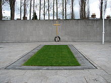 The burial spot of the leaders of the Rising, in the old prison yard of Arbour Hill Prison. The Proclamation of 1916 is inscribed on the wall in both Irish and English 1916 plot and memorial.jpg
