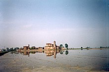 Fotografia a colori di una risaia che circonda un'abbazia.