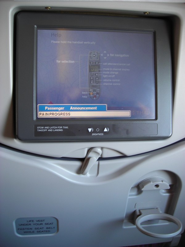 Control screen fixed to an economy class airline seat (Thai Airways International Airbus A340); the tray is stowed.