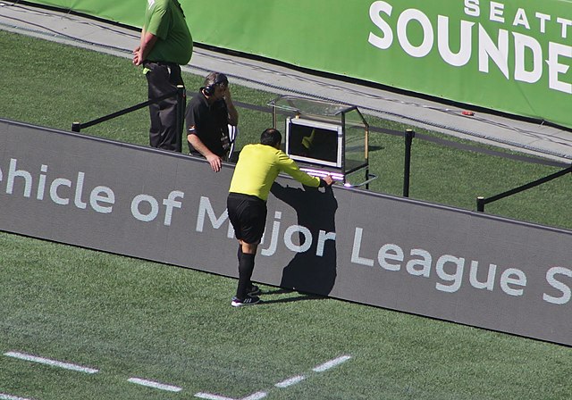 A Major League Soccer referee reviewing a play using a sideline monitor