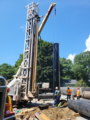 A well drilling rig with a crane moving a pipe