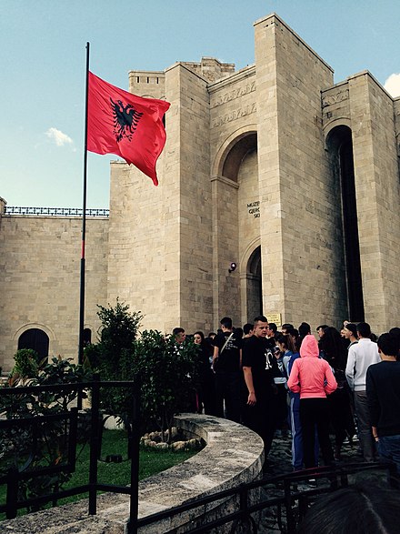 Albanian flag on a pole at the entrance of Krujë Castle