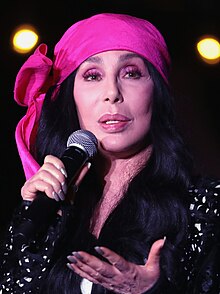 A photograph of Cher performing in London during her Here We Go Again Tour in October 2019
