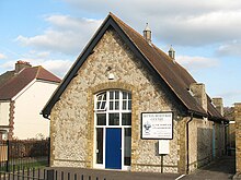 A photograph of small stone building with a v-shaped roof