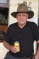 Fred Brophy sitting on the verandah of the Cracow Hotel, one of the two pubs he owns (the other being the Kilkivan Hotel). Fred, a fourth generation showman, runs Australia's last remaining boxing tent, known as Fred Brophy's Boxing Troupe. Note the can of XXXX Gold beer.