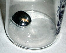 La cohésion de la goutte de mercure est plus forte que : (1) son adhésion avec le verre (pas de remontée sur la paroi verticale en contact) ; (2) la pesanteur s'exerçant sur le mercure (fort bombement de la goutte).