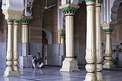 Man sitting between columns of a mosque India Delhi