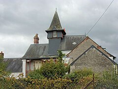 Farbfoto eines Hauses, dessen Dach von einem Schieferturm überragt wird.