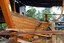 Construction of the Naga Pelangi in 2004, a Malaysian pinas, using traditional Austronesian edge-dowelled techniques. Note the protruding dowels on the upper edges of the planks and the fiber caulking in the seams. Naga Pelangi building without frames.jpg