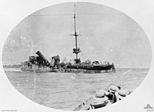 A broadside view of the wrecked Emden after her encounter with HMAS Sydney. Crew huddle on the wreck, awaiting rescue by Sydney.