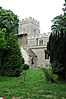 A stone church seen between trees, with a tower and part of the nave, both battlemented