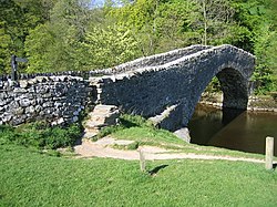 A single-span arched stone bridge over a watercourse