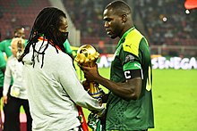 Koulibaly (a destra) porge al commissario tecnico del Senegal Aliou Cissé il trofeo della Coppa d'Africa 2021