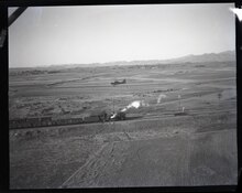 MARINE GRASSHOPPER PLANE of Major General Louis E. Woods First Marine Aircraft Wing flies low over a train carrying vitally needed coal between T'ang Shan and Tientsin.  Planes patrol the tracks for breaks carrying mail and passengers at the same time.